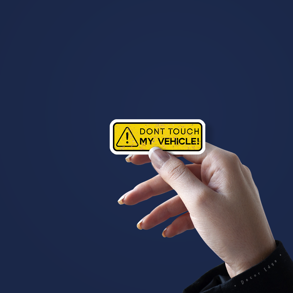 Hand holding a yellow dont touch my vehicle sticker with warning symbol on a dark blue background